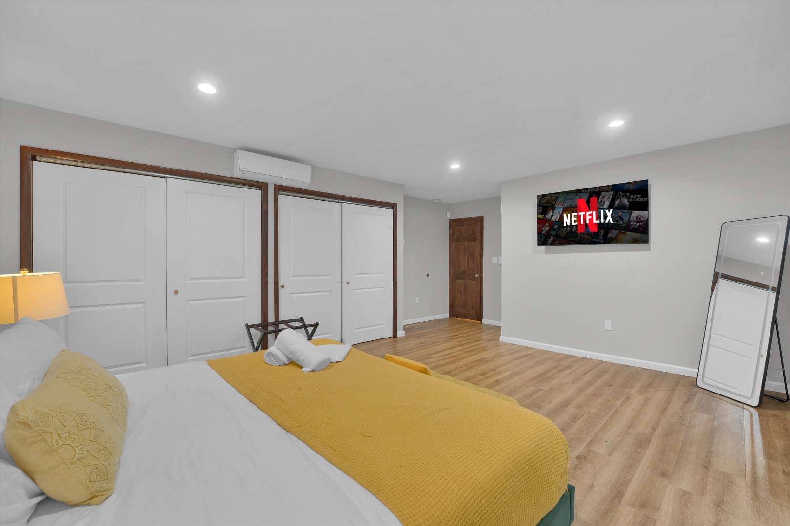 Relax in comfort with a flat-screen Smart TV, light wood floors, and soft bedding.