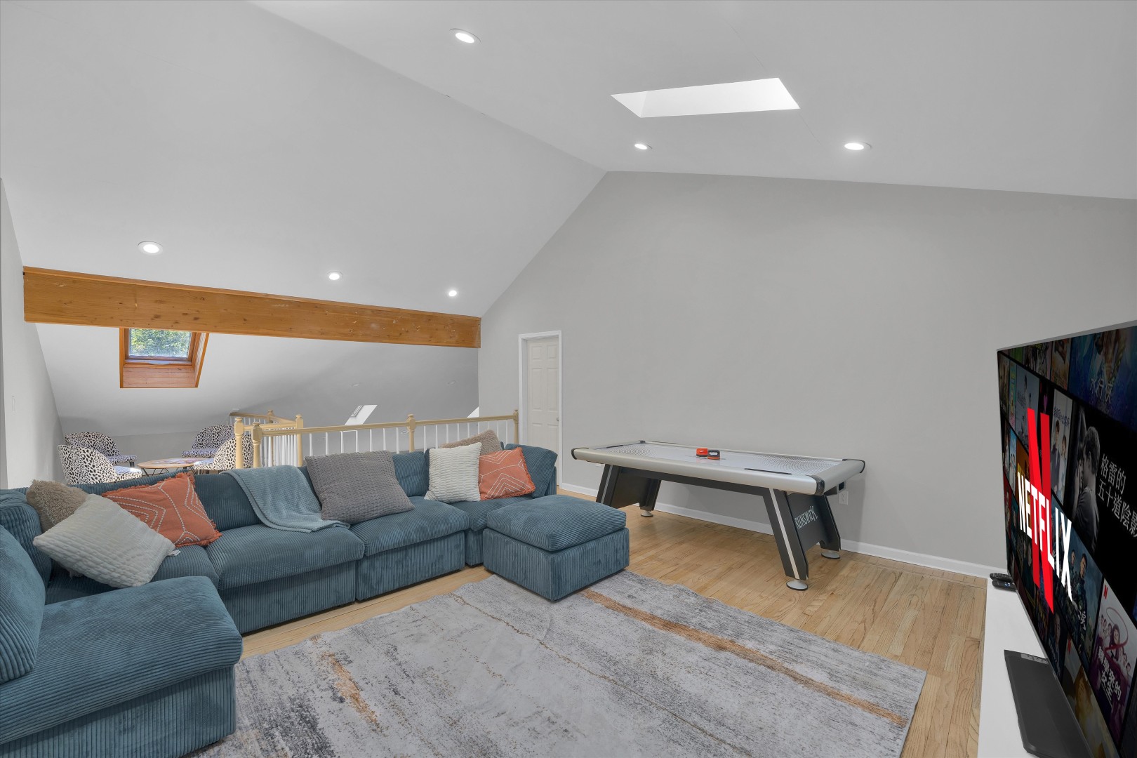 The ultimate hangout spot - featuring a deep L-shaped sofa, smart TV setup, air hockey table, and plenty of space to relax.