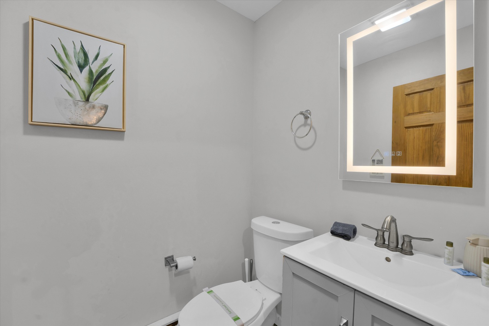 Freshen up in this clean and convenient half-bath, featuring an illuminated mirror and a simple, elegant design.