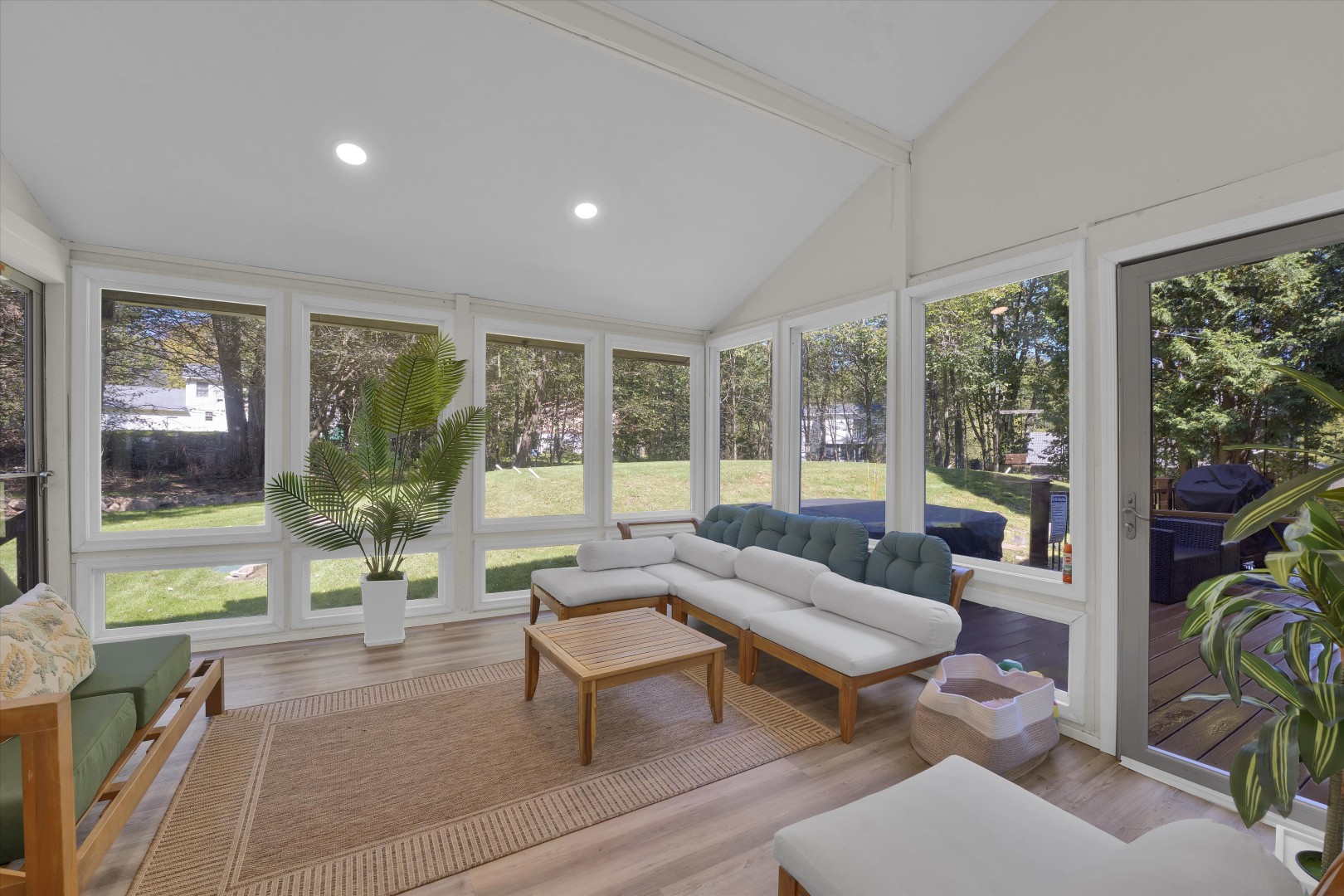 Bright and airy sunroom sanctuary with sprawling window views, woven accents, and cozy lounge seating.