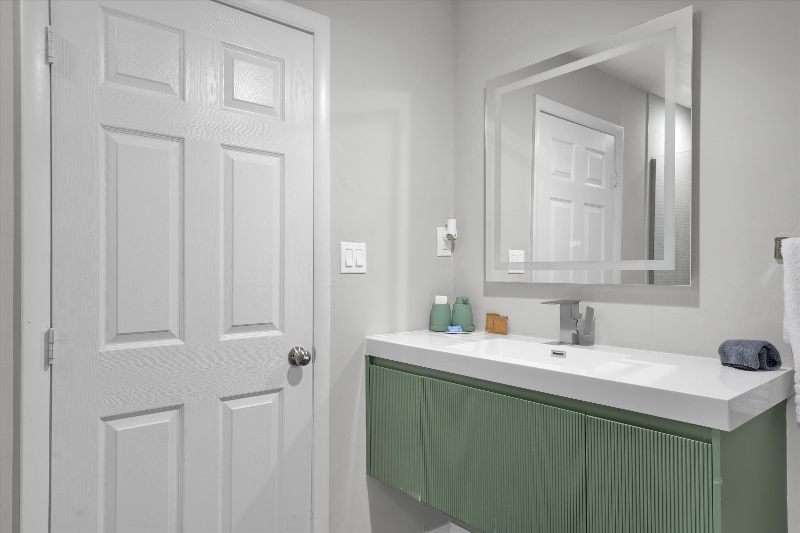 Bright bathroom with a clean sage vanity, sleek fixtures, and fresh towels.