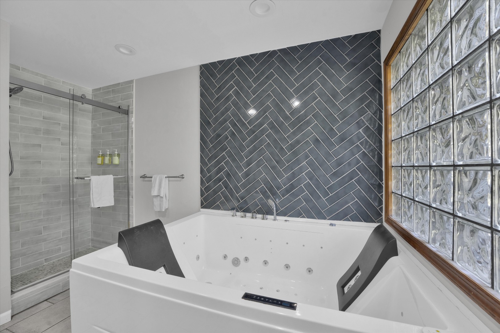 Unwind in the deep Jacuzzi soaking tub, complete with a dark herringbone tile accent wall.