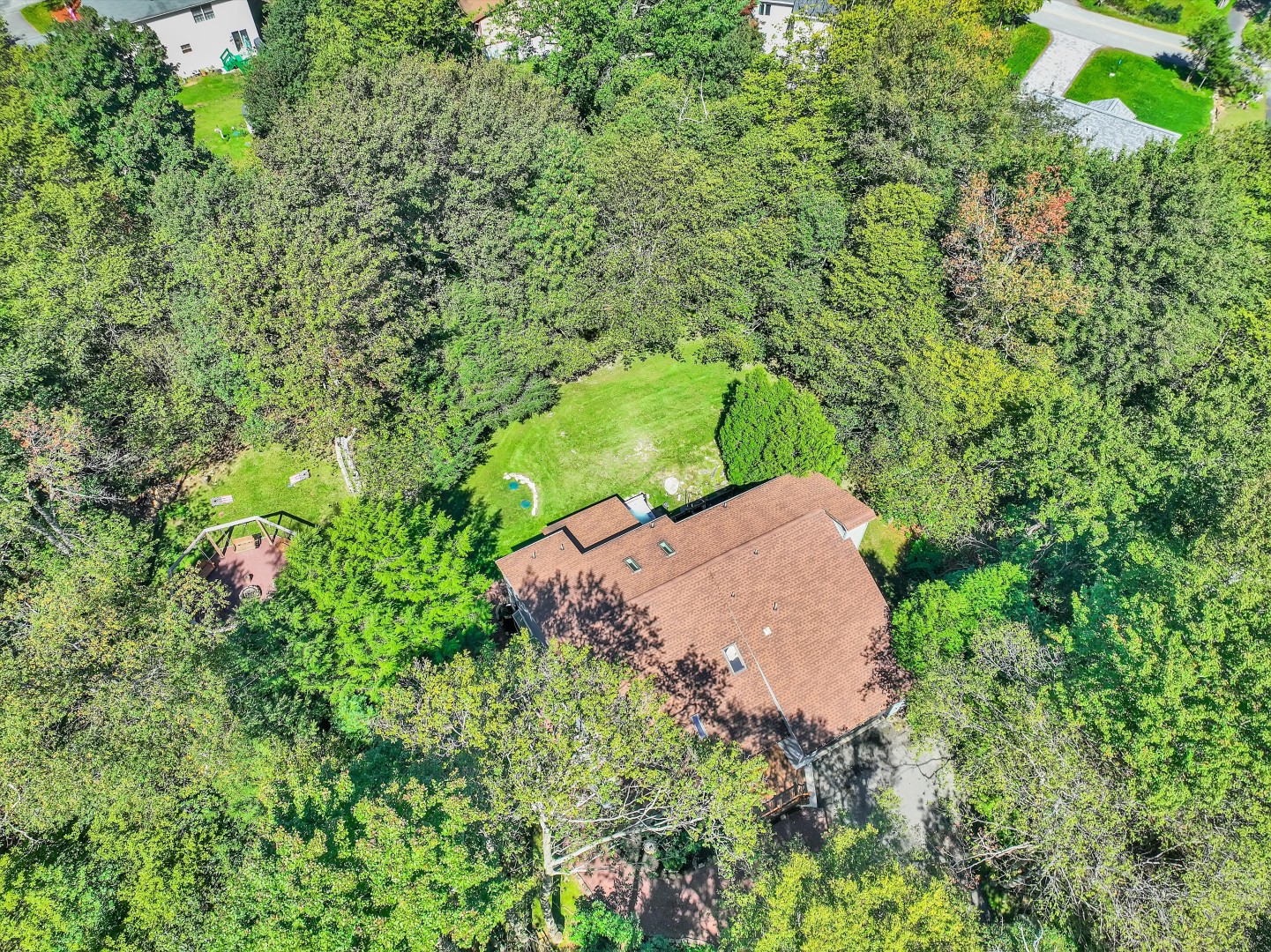 Bird’s-eye view showing the private home nestled snugly within a dense, green forest setting.
